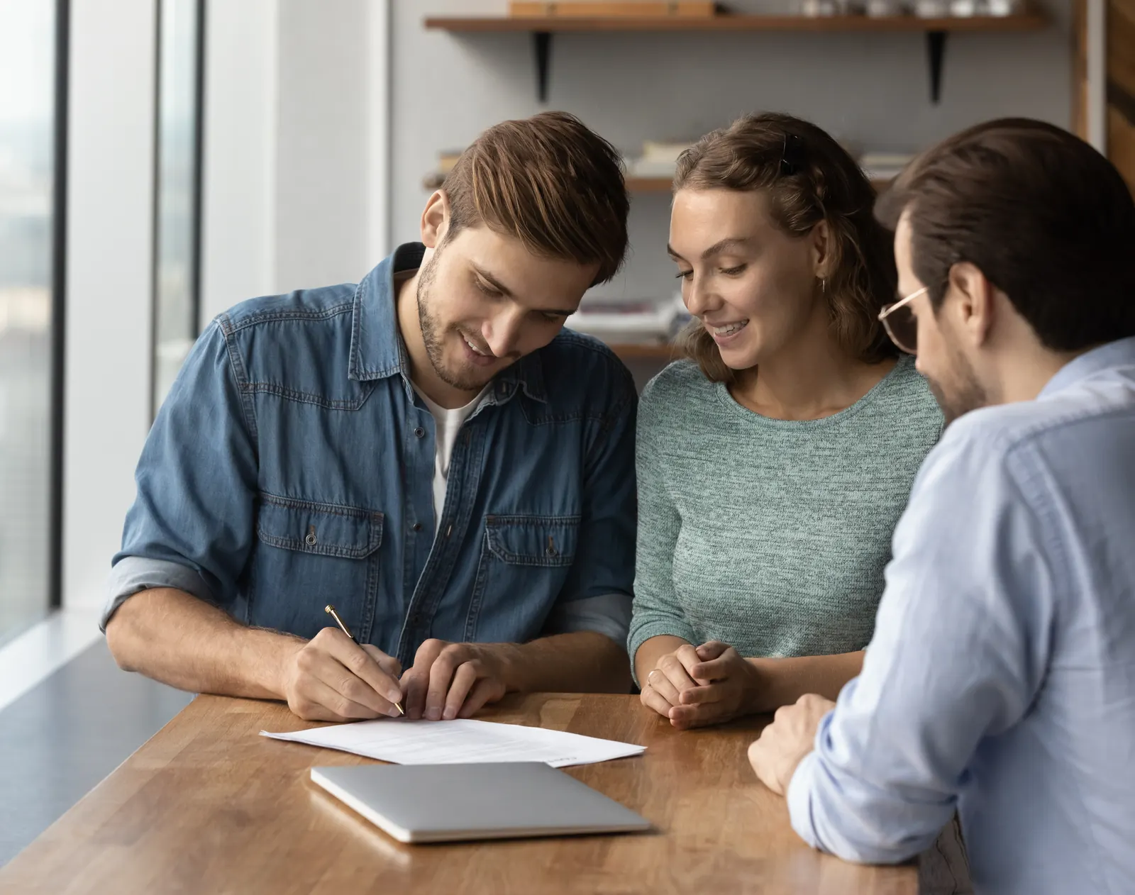 A young couple signing their mortgage paperwork with an advisor